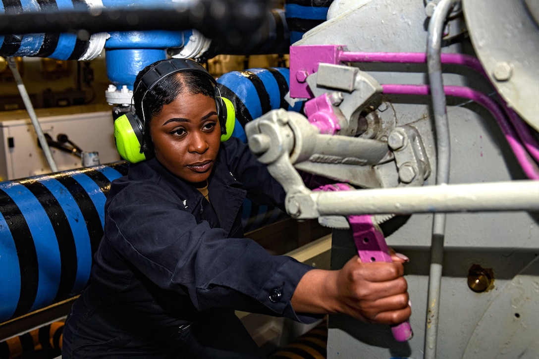 A service member turns a valve.