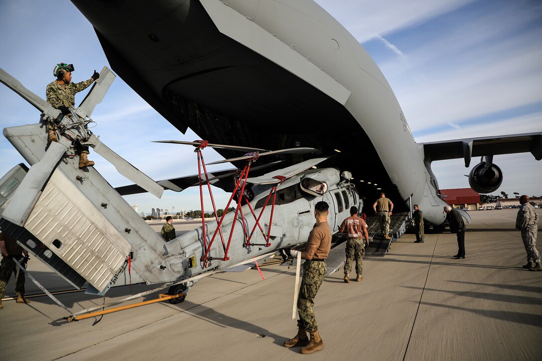Navy personnel and loadmasters from the 89th Airlift Squadron load a MH-60S Seahawk helicopter onto a 445th Airlift Wing C-17 Globemaster III at Naval Base Coronado, California, Jan. 24, 2019. Members of the 445th Airlift Wing Operations Group performed their annual training at Naval Amphibious Base, Coronado and Marine Corps Air Station Miramar near San Diego, California Jan. 18-27, 2019. The training included water survival, Survival, Evasion, Resistance and Evasion, and low altitude flying. (U.S. Air Force photo/Master Sgt. Patrick O’Reilly)
