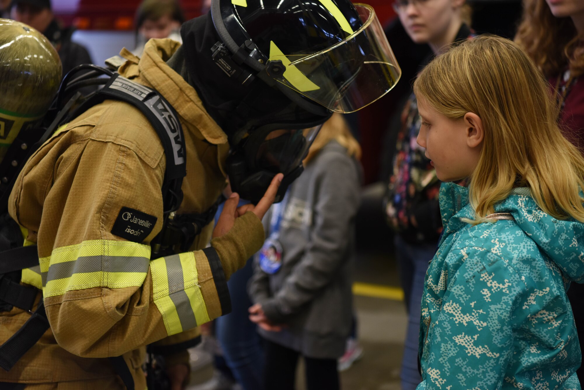 Airman 1st Class Kayla Jerido, 86th Civil Engineer Squadron firefighter shows Lucena Hanna her fire protection gear during Young Women in Aviation Day on Ramstein Air Base, Germany, March, 9, 2019. Jerido showed how fast she could put on her suit and equipment, while also showing the many instruments that protect her during a fire.