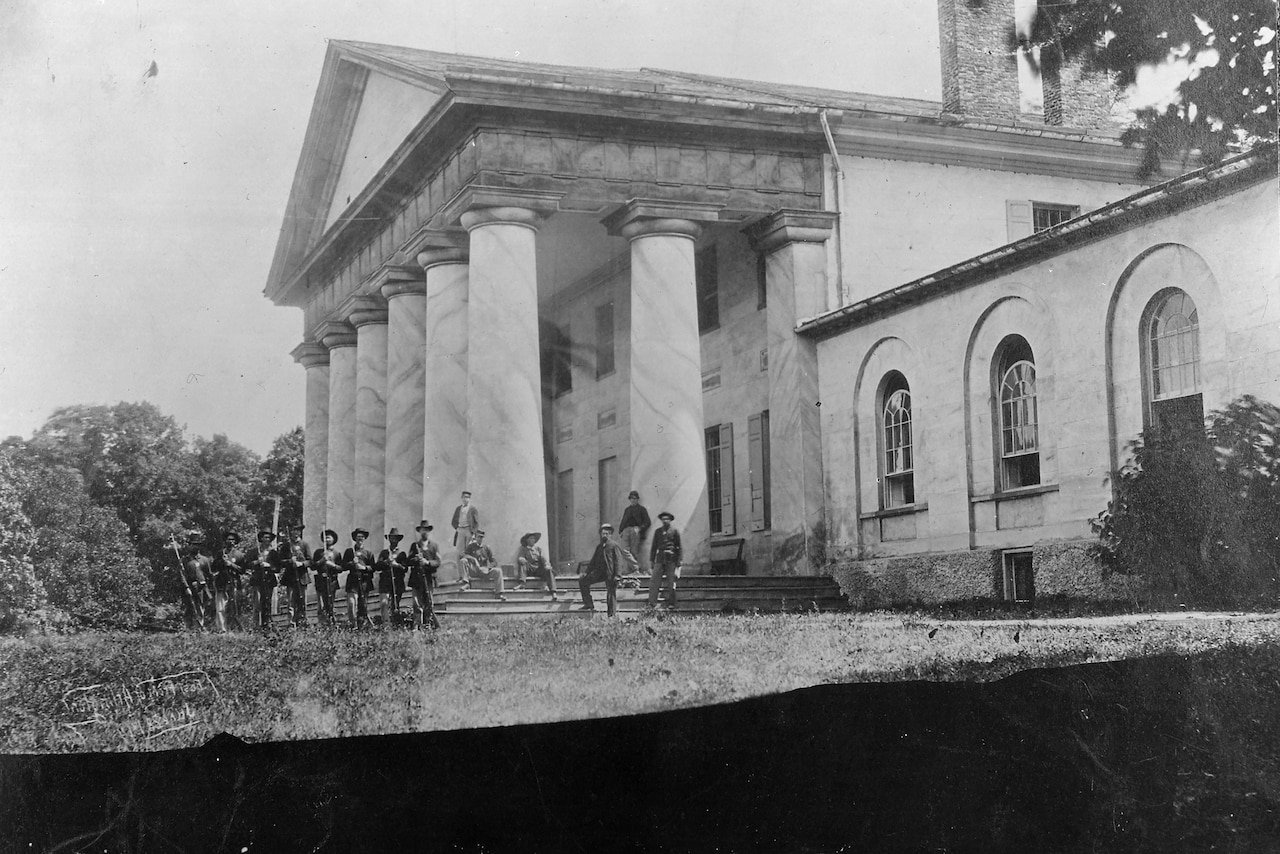 Soldiers stand in front of a mansion.