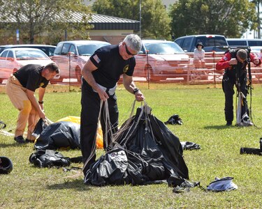 Members from all 3 Army teams, Golden Knights, Silver wings and Black Daggers gather up their parachutes after a successful jump during the training at Homestead.