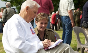 World War II Veteran Richard Yates signs a book for a French civilian before a ceremony at Amfreville, Normandy, France