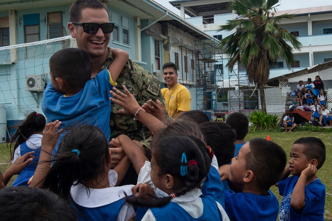 A service member interacts with students.