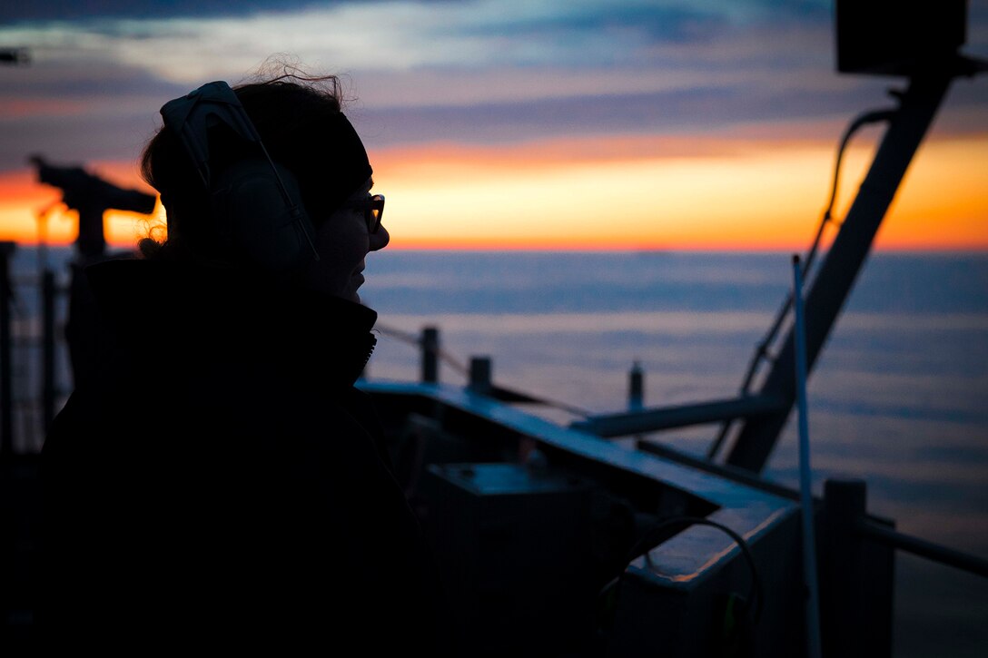 A service member stands lookout on a ship.