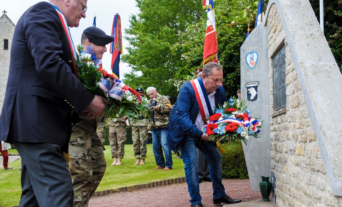 U.S. Army Staff Sgt. Daniel Desaulniers, 101st Airborne Division, lays a wreath with French civilians in Beuzeville-Au-Plain, France