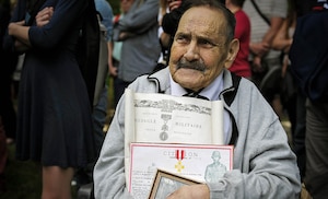 Geoffroy Francis, 83, French Army World War II veteran, grasp an old photo and his medals from WWII during a ceremony in Coigny, France
