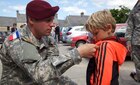 Sgt. Aaron Dawson pins U.S. Army Parachute Rigger wings to a French childs collar in Negreville, France