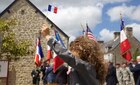 A French child waves a French flag at a ceremony in Negreville, France