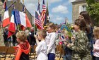 French school children wave American and French Flags during a ceremony in Negreville, France