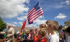 French school children wave American and French Flags during a ceremony in Negreville, France
