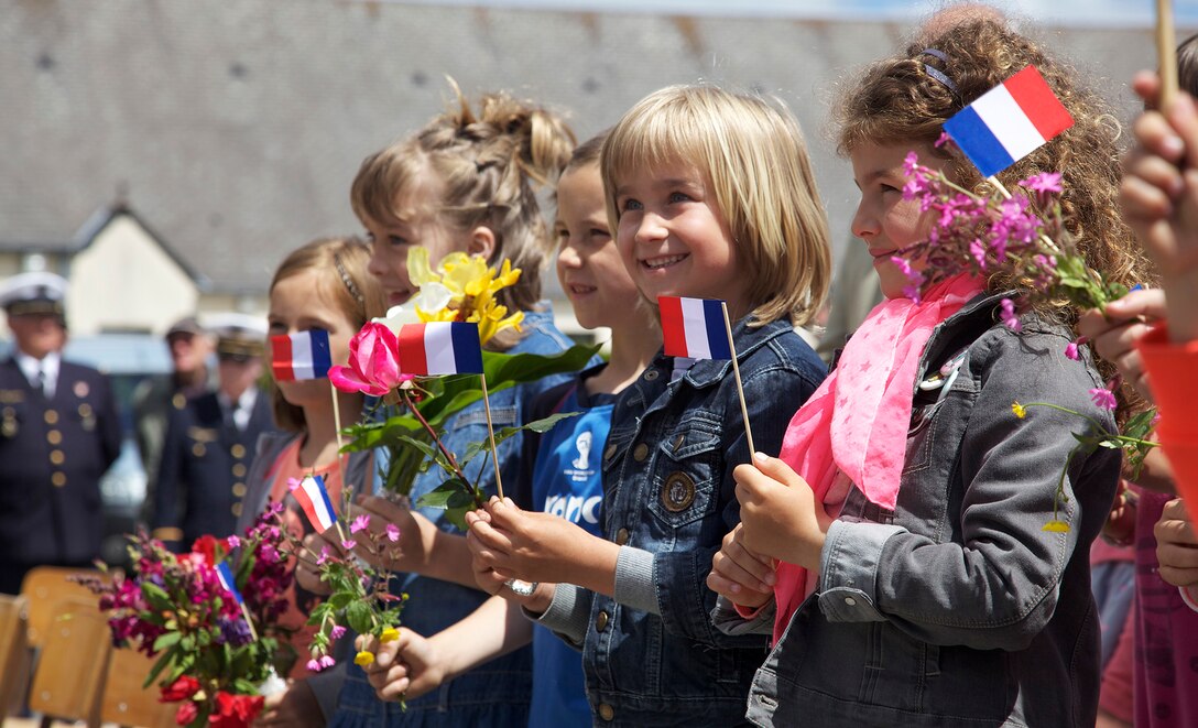 French school children wave French Flags during a ceremony in Negreville, France