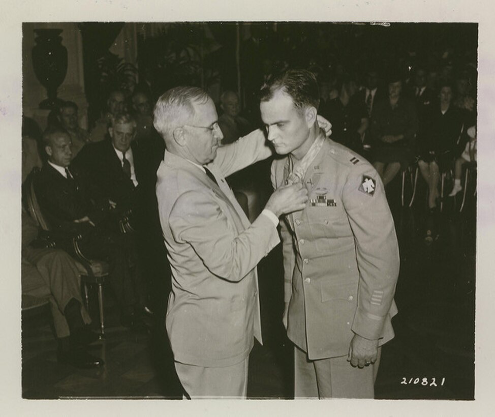 A man puts a medal around the neck of a soldier.