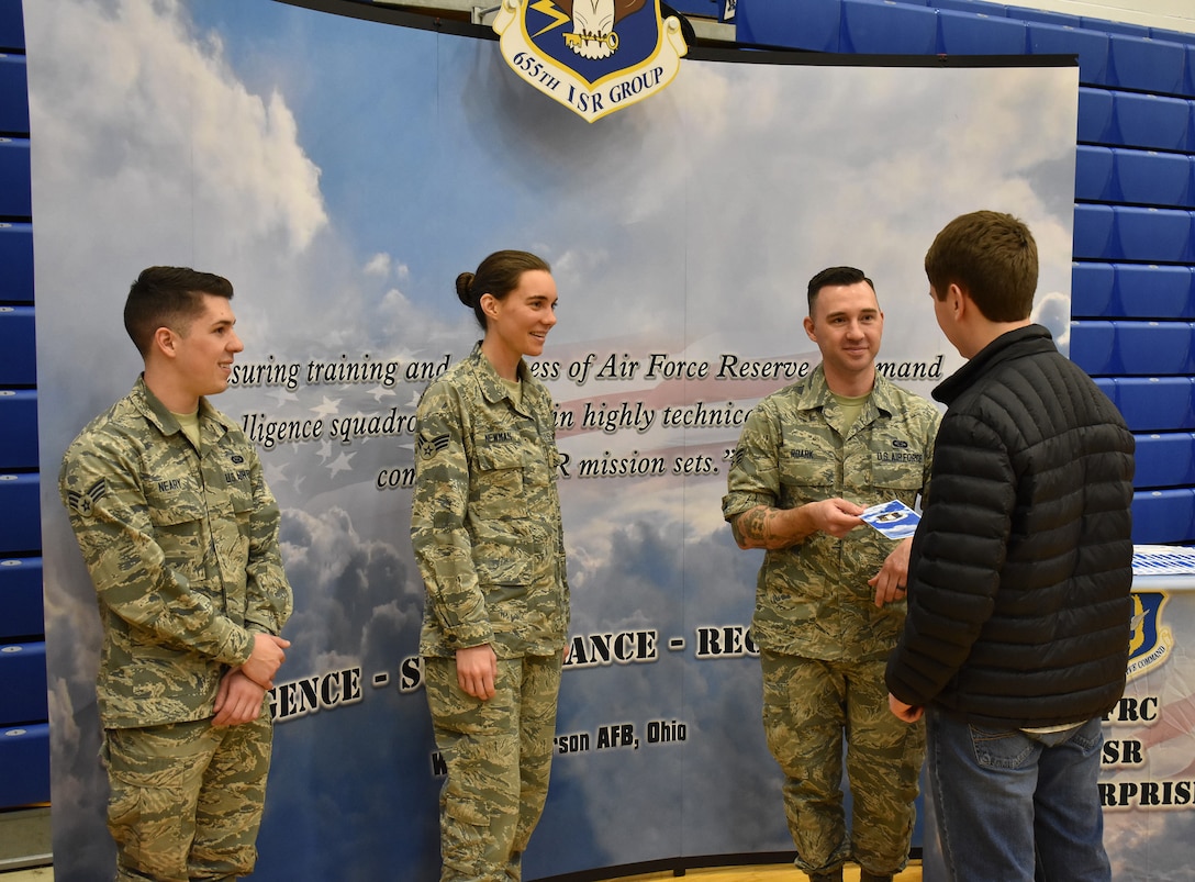 655th Intelligence, Surveillance, and Reconnaissance Wing, 71st Intelligence Squadron analyst Senior Airman Roark hands a senior class student an information brochure at Xenia High School, Xenia, Ohio, March 13, 2019.  Roark and other members of the 71st and 14th intelligence squadrons participated in a career day held at the school to promote the 655th mission, as well as the opportunities and benefits available in the United States Air Force Reserve.  The event was sponsored by the Ohio Means Jobs Greene County office.