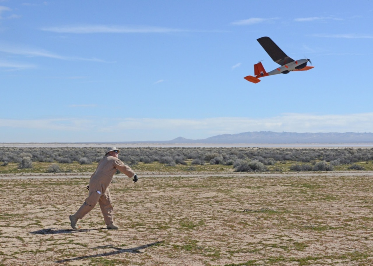 A man hand launches a small airplane.
