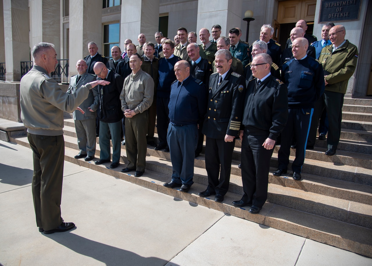 An American military officer speaks to military officers from NATO nations.