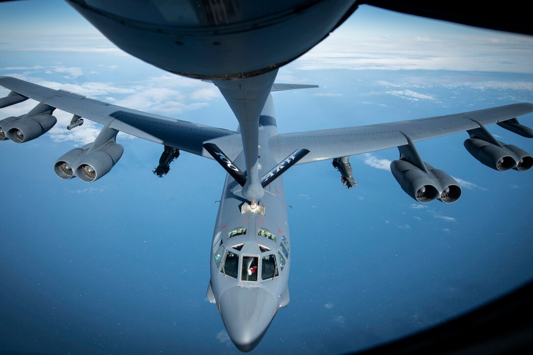 A military plane gets fuel from another military plane in midair.