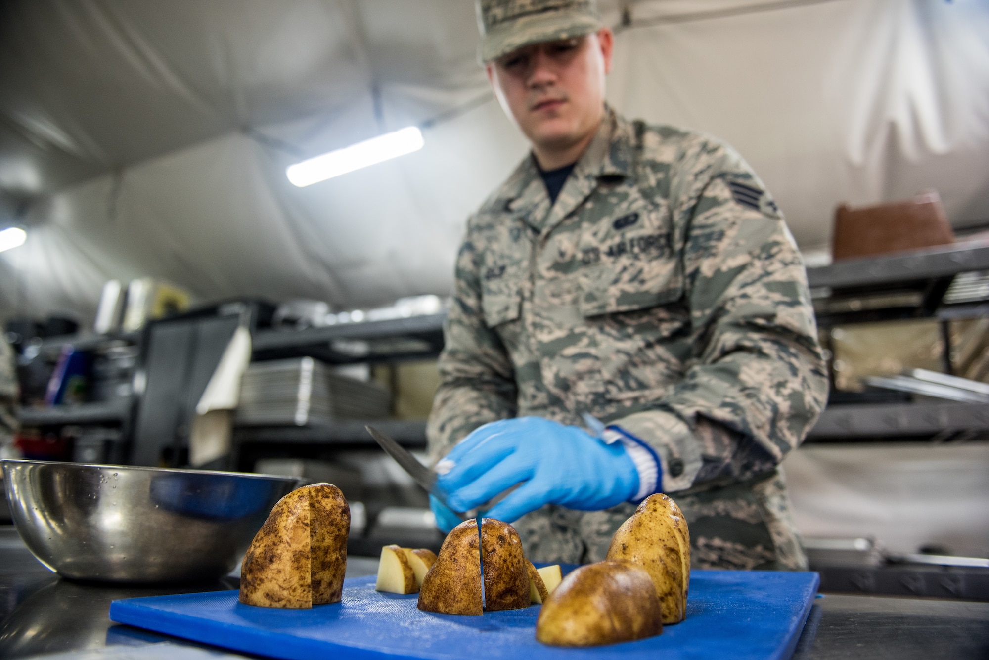 Senior Airman Bryan Seijo, 512th Memorial Affairs Squadron lodging specialist, slices potatoes during the John L. Hennessy food service competition at Dobbins Air Reserve Base, Georgia, March 9, 2019. The 512th MAS cooking team were tasked with prepping, cooking and serving food from noon to 5 p.m. (U.S. Air Force photo by Staff Sgt. Damien Taylor)
