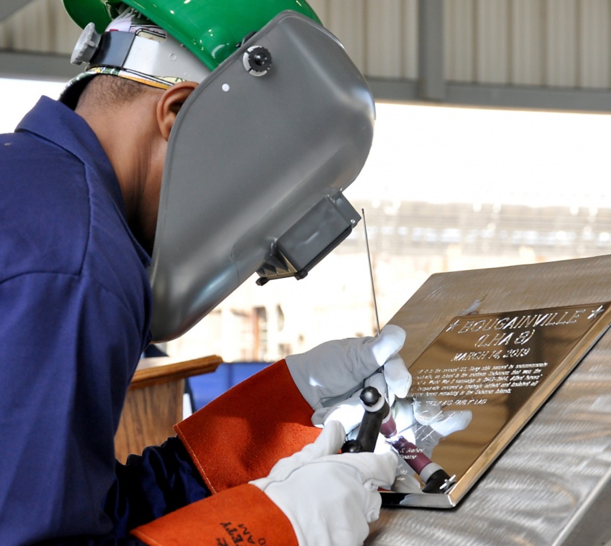 Ingalls Shipbuilding welder Cedric Harman welds Ship Sponsor Ellyn Dunford’s initials into a steel plate during the keel authentication ceremony of the future USS Bougainville (LHA 8) at Huntington Ingalls Industries Pascagoula shipyard March 14.