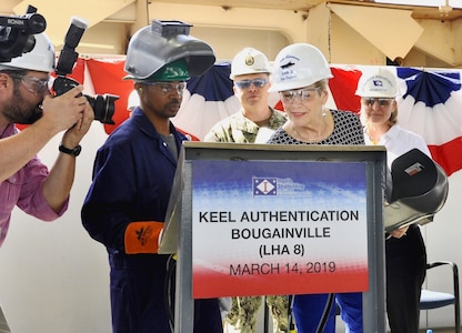 Ship Sponsor Ellyn Dunford traces her initials before Ingalls Shipbuilding welder Cedric Harman welds them into a steel plate to be fastened to the ship during the keel authentication ceremony of the future USS Bougainville (LHA 8) at Huntington Ingalls Industries Pascagoula shipyard March 14.