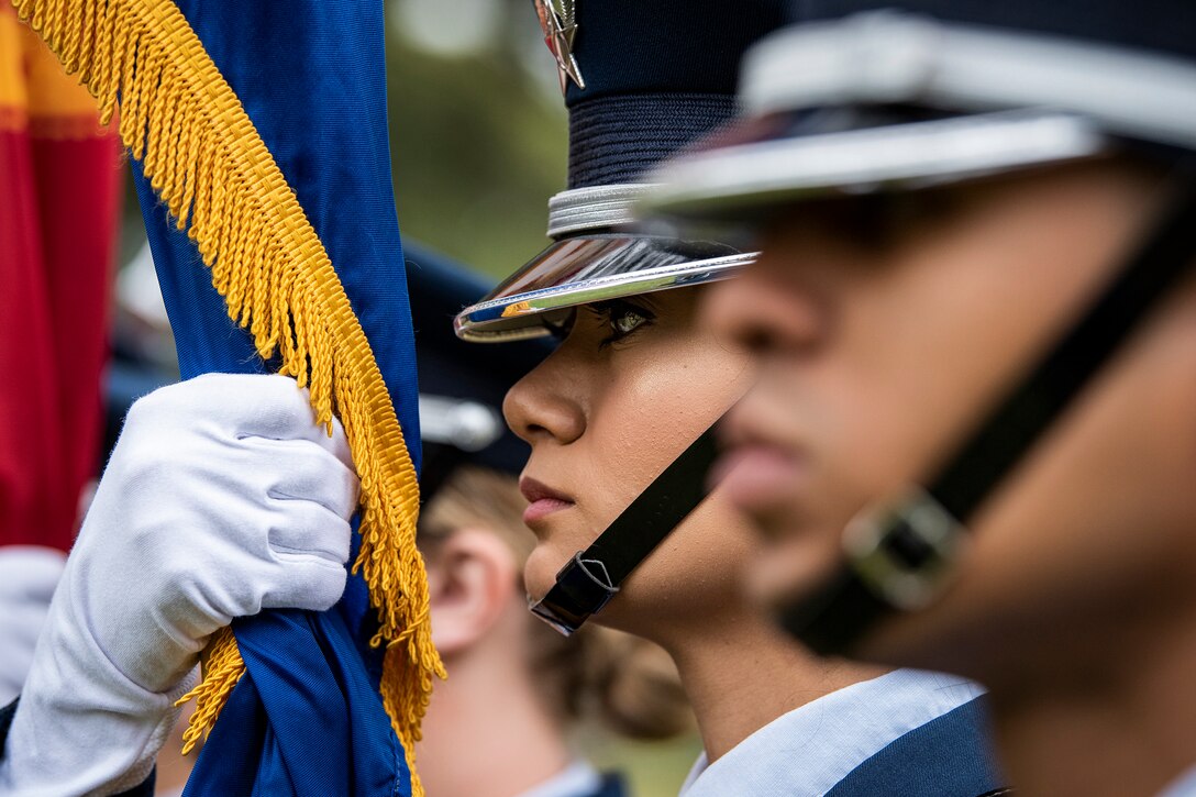 An airman holds a flag close to her face.