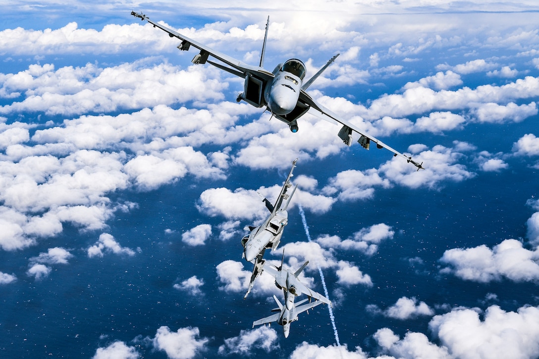 Four jets flying above clouds.