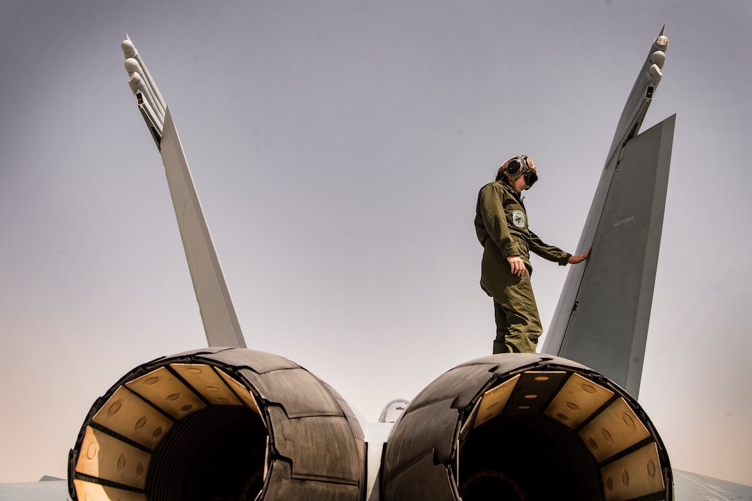 A sailor stands on top of a jet.