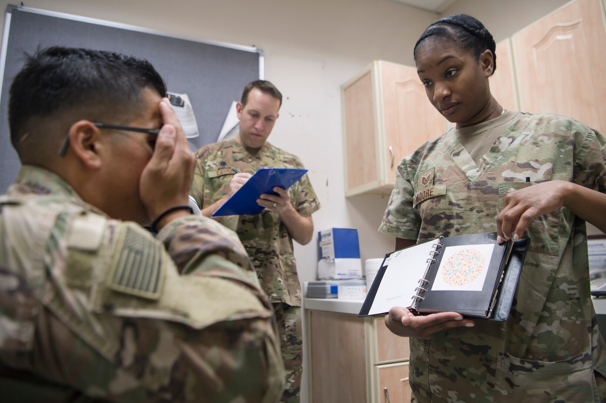 U.S. Air Force Tech. Sgt. Marquita Moore, right, 379th Expeditionary Medical Group (EMDG) optometry NCO in charge from Al Udeid Air Base (AUAB), Qatar, conducts an eye exam for a U.S. Army Soldier as U.S. Air Force Lt. Col. Peter Carra, 379th EMDG optometry officer in charge, documents data March 9, 2019, at Camp As Sayliyah (CAS), Qatar. Moore and Carra travel to CAS once a week to provide eye care for Soldiers who, in turn, fabricate glasses prescribed for Airmen at AUAB and servicemembers at other deployed locations throughout U.S. Central Command.  (U.S. Air Force photo by Tech. Sgt. Christopher Hubenthal)