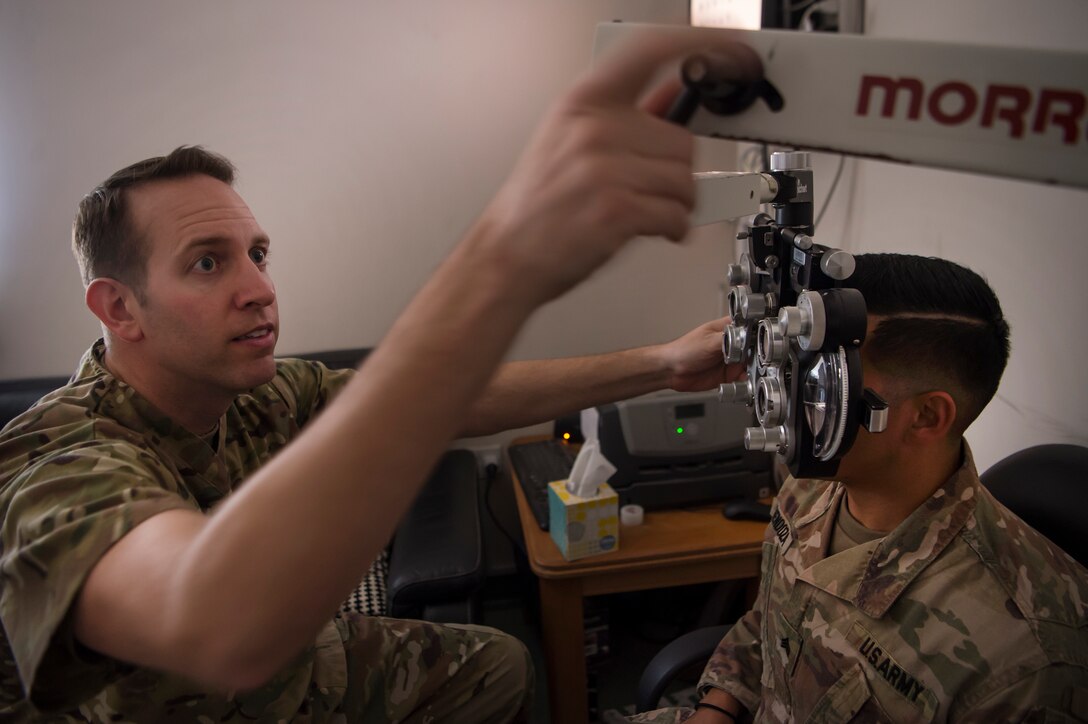 U.S. Air Force Lt. Col. Peter Carra, 379th Expeditionary Medical Group (EMDG) optometry officer in charge, performs an eye exam for a U.S. Soldier March 9, 2019, at Camp As Sayliyah (CAS), Qatar. Carra and Tech. Sgt. Marquita Moore, 379th EMDG optometry NCO in charge, travel to CAS once a week to provide eye care for Soldiers who, in turn, fabricate glasses prescribed for Airmen at Al Udeid Air Base, Qatar, and servicemembers at other deployed locations throughout U.S. Central Command.  (U.S. Air Force photo by Tech. Sgt. Christopher Hubenthal)