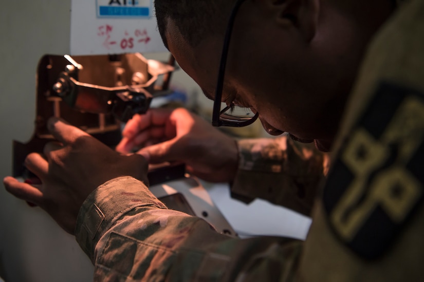 U.S. Army Spc. Justin Jones, 354th Medical Company Logistics Support optical laboratory specialist, 8th Medical Brigade, Area Support Group - Qatar, fabricates lenses for glasses March 9, 2019, at Camp As Sayliyah, Qatar. Jones is part of a team that grinds and frames glasses from data provided by a U.S. Air Force optometry team from Al Udeid Air Base, Qatar. (U.S. Air Force photo by Tech. Sgt. Christopher Hubenthal)