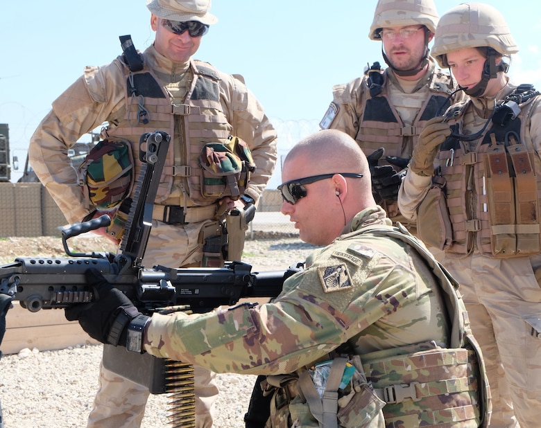 Staff Sergeant (P) Andrew Pretty gives pre-marksmanship instruction on the M249 SAW to 3 Belgian Coalition Soldiers.