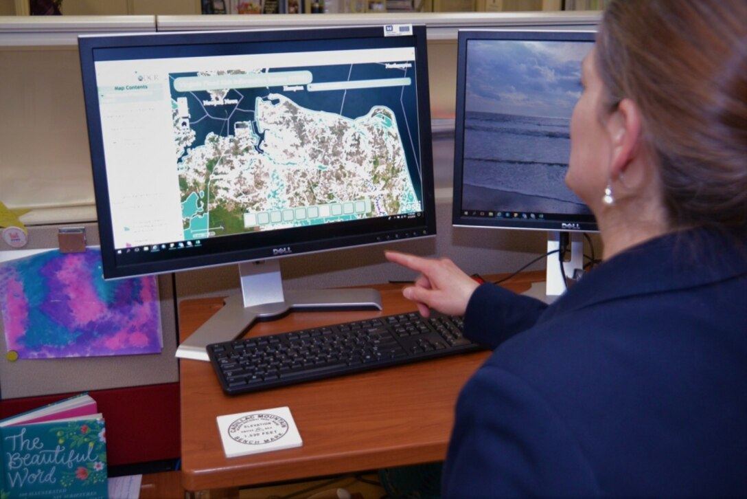 Woman in blue jacket points to a computer showing flood areas in Virginia