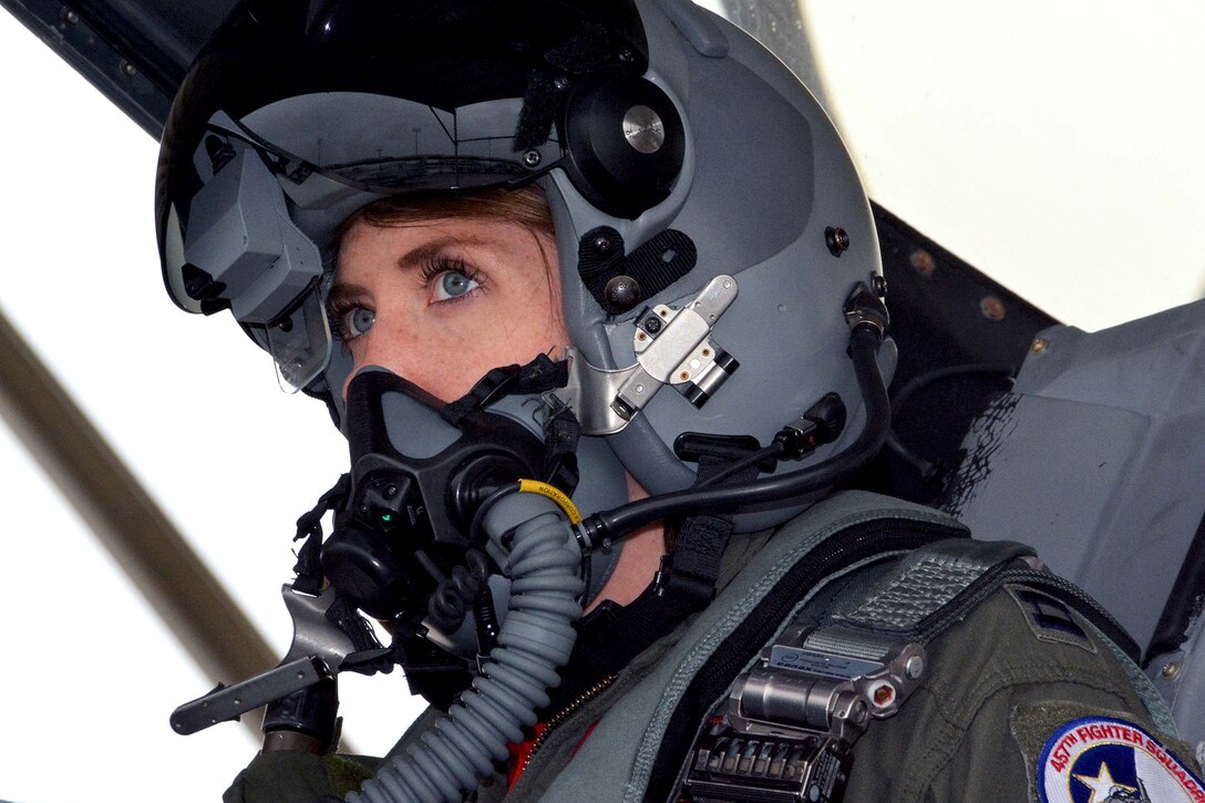Close-up of a female pilot with helmet on sitting inside an F-16 Fighting Falcon.