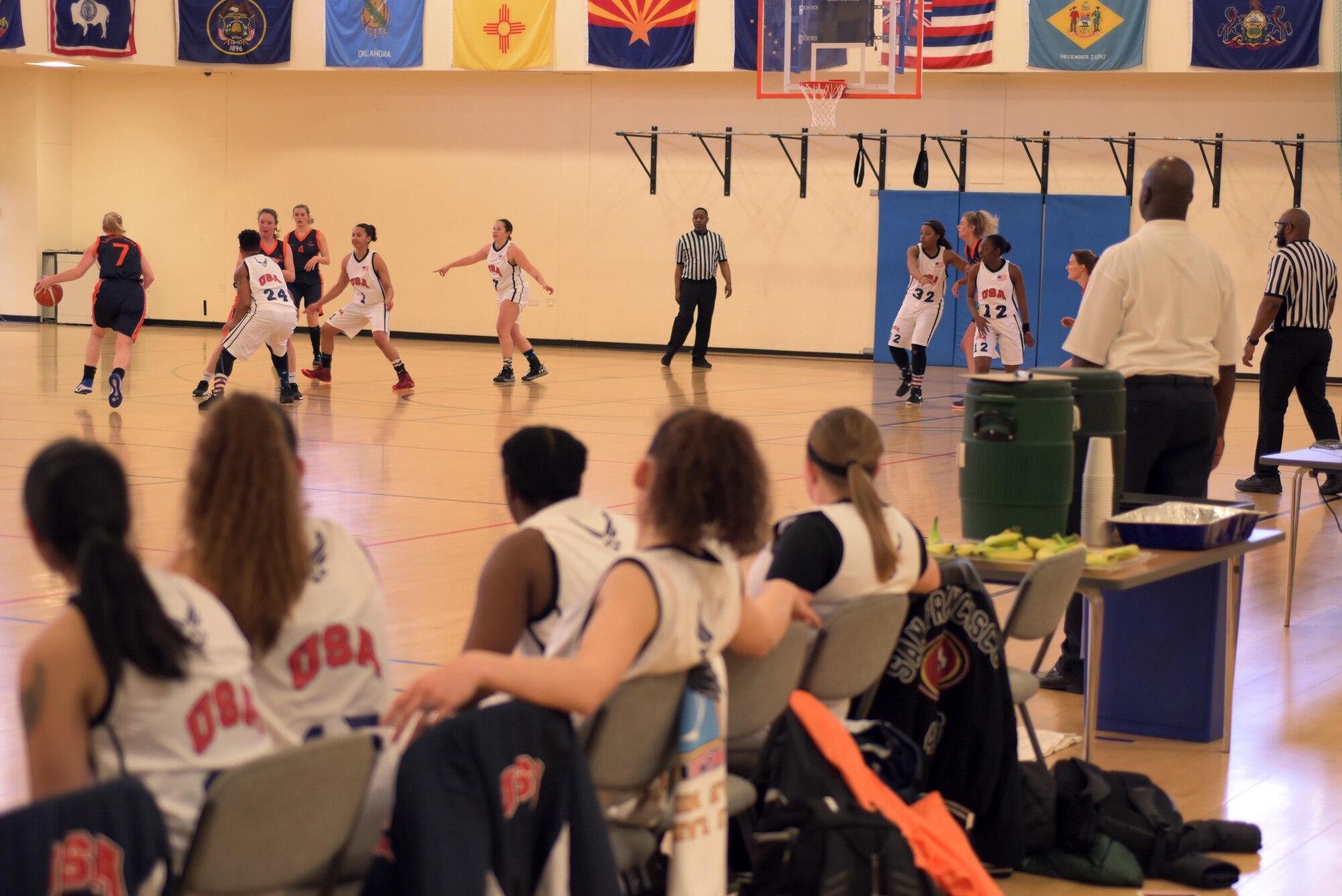 The basketball team from U.S. Air Forces in Europe Air Forces Africa looks on as their teammates play defense against the Air Force team from the Netherlands at RAF Mildenhall, England, March 12, 2019,. This international sports championship brought together the contributing nations within Allied Air Command with an opportunity for friendly sporting competition. (U.S. Air Force photo by Senior Airman Benjamin Cooper)