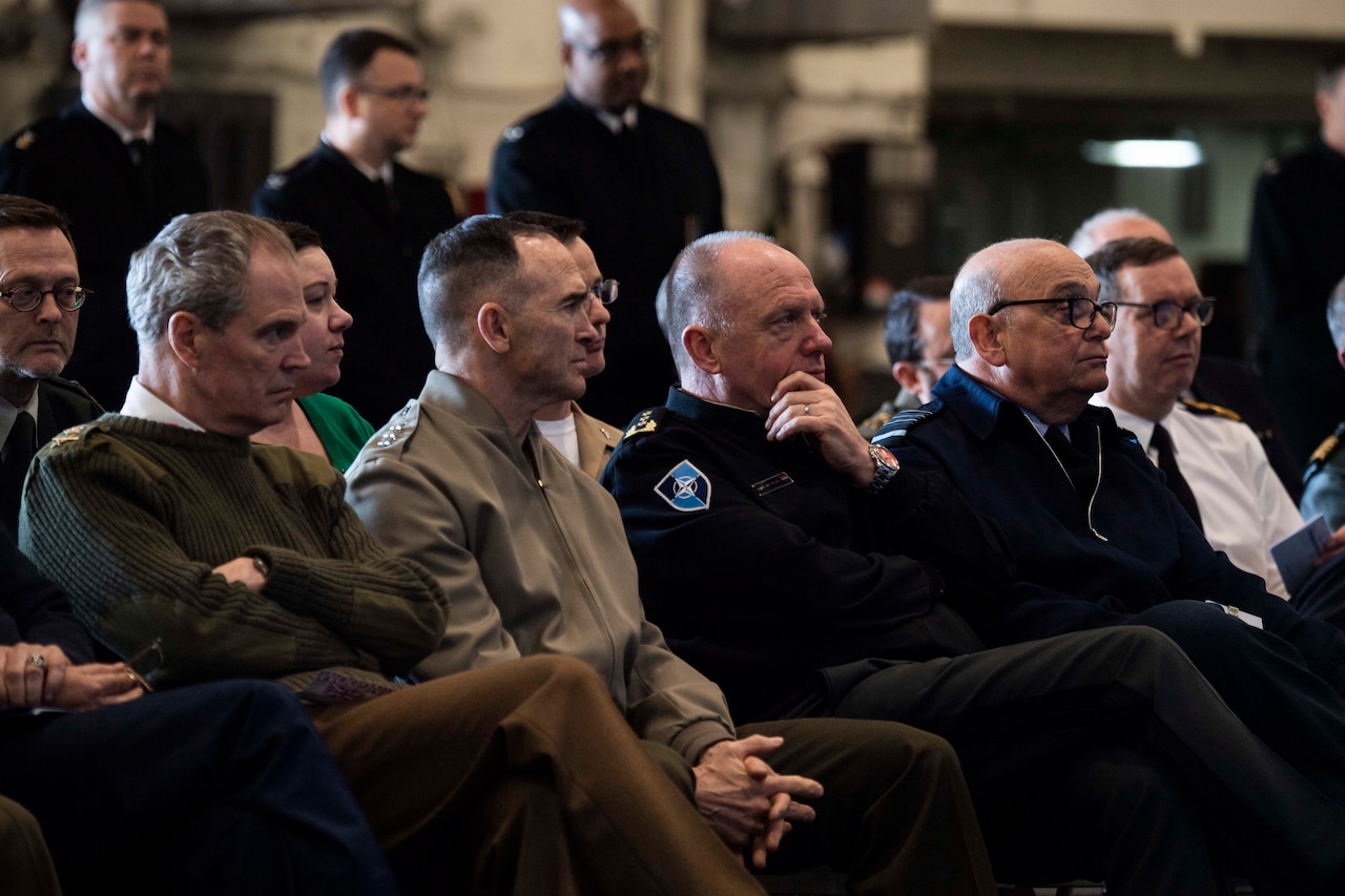 NATO military officers listen to speech.