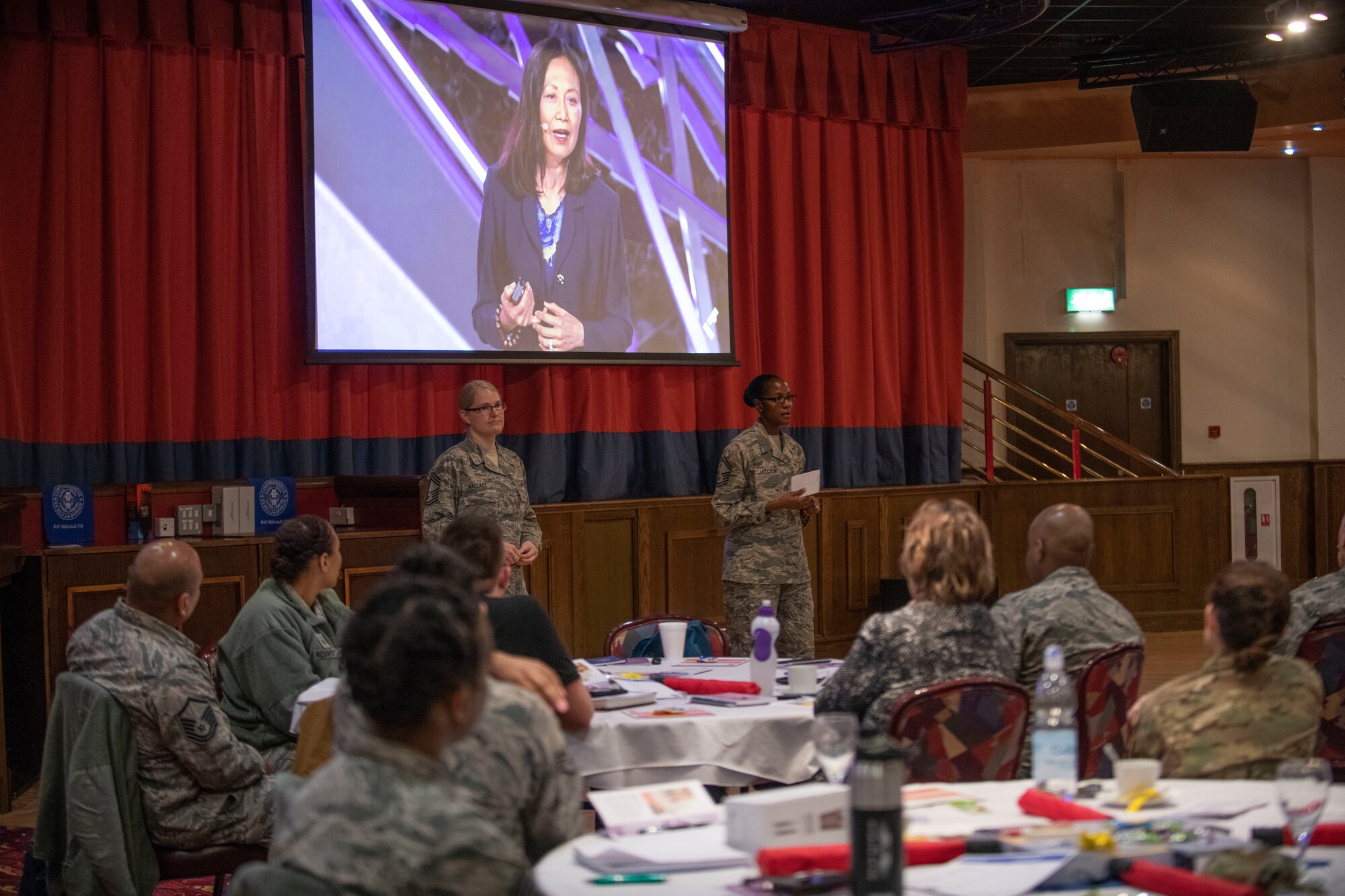 U.S. Air Force Chief Master Sgt. Tracy Wallace, 100th Force Support Squadron superintendent, and U.S. Air Force Senior Master Sgt. Terry Jackson, 100th Force Support Squadron lodging superintendent, speak to Airmen at RAF Mildenhall, England, March 14, 2019. The theme of this year’s event was women leaders and included CEOs, human rights activists and motivational speakers. (U.S. Air Force photo by Senior Airman Luke Milano)