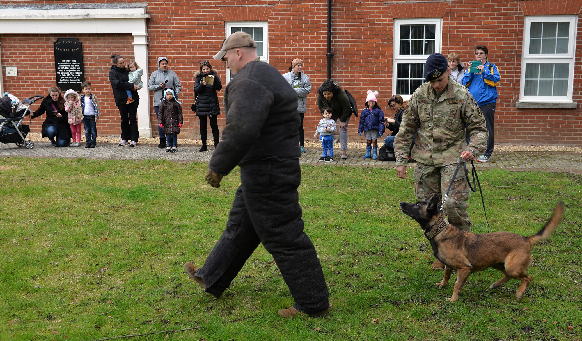 U.S. Air Force Staff Sgt. Kristina Santos, 100th Security Forces Squadron military working dog handler, holds onto MWD Ukkie as the K9 keeps a watchful eye on “bad guy” Staff Sgt. Louis Hurbis, 100th SFS MWD handler, during a demonstration on RAF Mildenhall, England, March 13, 2019. The demonstration was part of activities to celebrate K9 Veterans’ Day and Team Mildenhall children did crafts and had the chance to pet a retired military working dog. (U.S. Air Force photo by Karen Abeyasekere)
