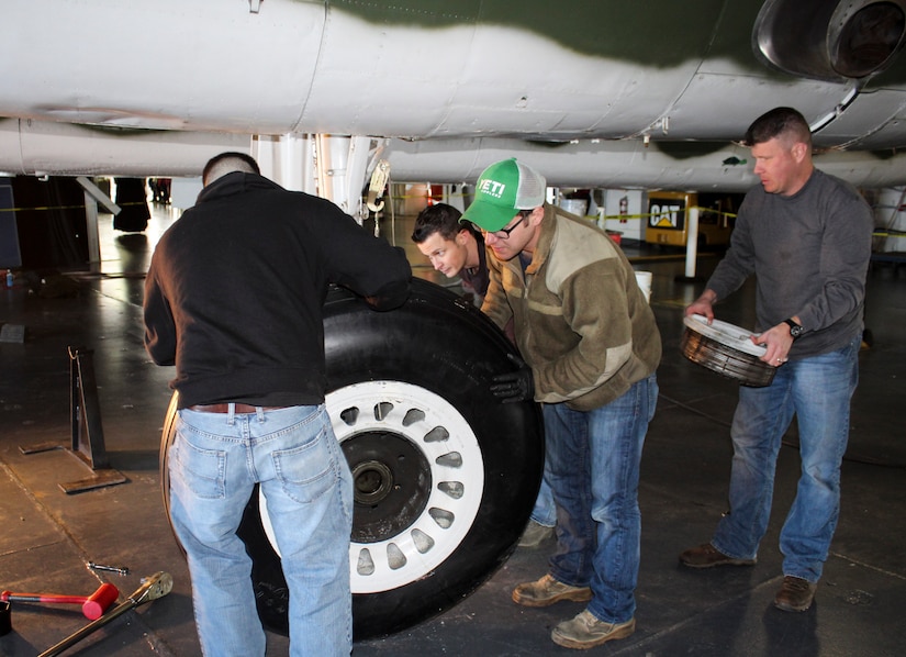 Master Sgt. Ron Williams holds the outer brake assembly of a B-25 at Patriots Point Martime Museum in Mount Pleasant, S.C., as Tech. Sgt. Nathon Andrews (background), Staff Sgt. Mark Jacobs (right) and Airman 1st Class Christopher Garren (left) slowly remove the wheel and tire assembly from the axle.