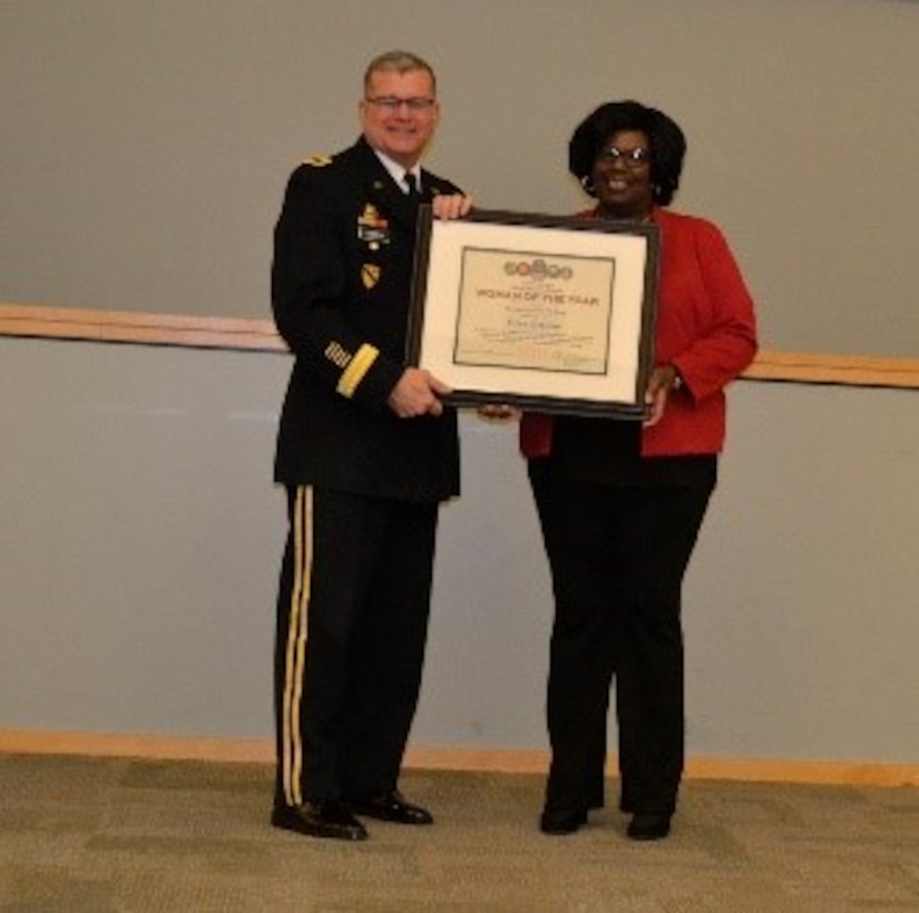 Army Brig. Gen. Mark Simerly, DLA Troop Support commander, left, presents Robin Whaley, right, Subsistence supply chain supervisor, a plaque on behalf of Gina Breleur, a Troop Support Europe and Africa employee, for her exemplary model of public service and government leadership during the Women’s History Month Program March 13. Breleur was selected Woman of the Year in the non-supervisory GS-9 and below category. (Photo by Alexandria Brimage-Gray)
