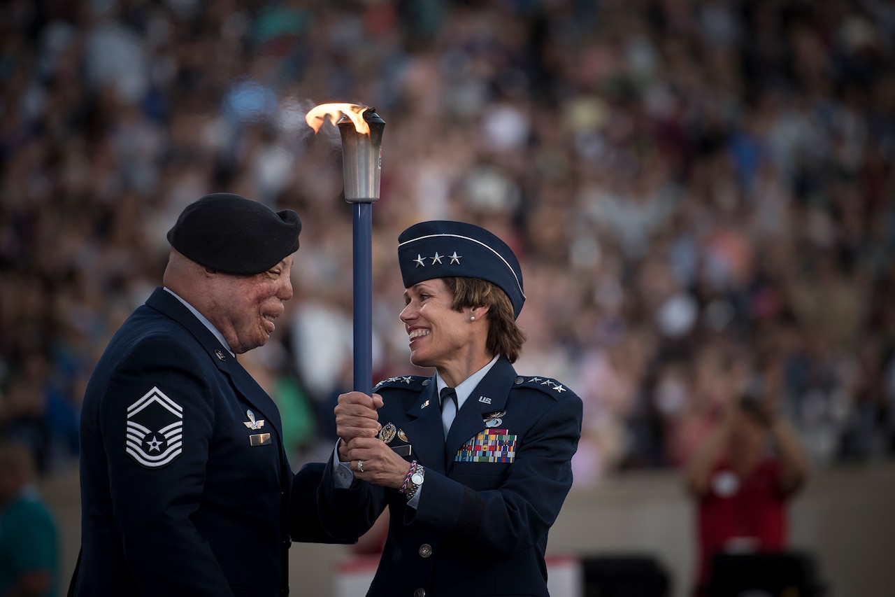 Two people hold a torch.