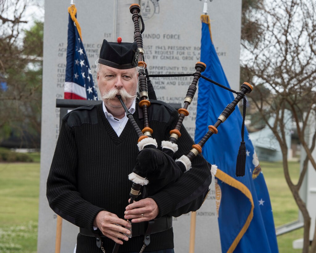bagpiper playing song with flags behind them