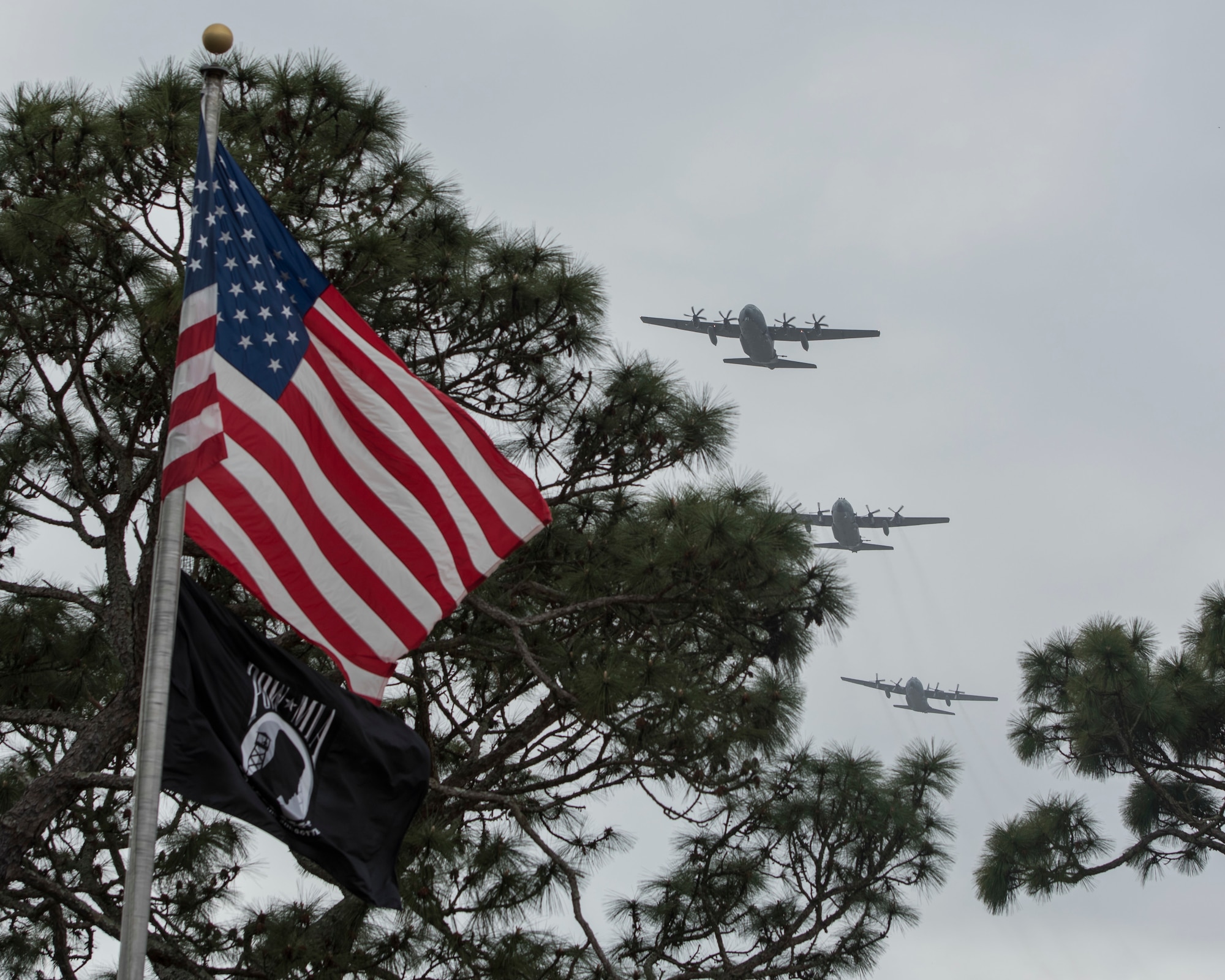 US and POW flags with three gunships flying in the background