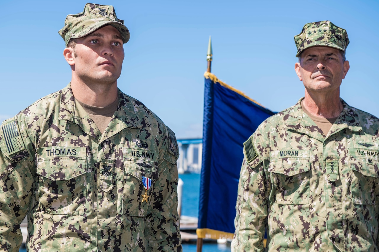 A sailor stands at attention wearing a Silver Star on his uniform.