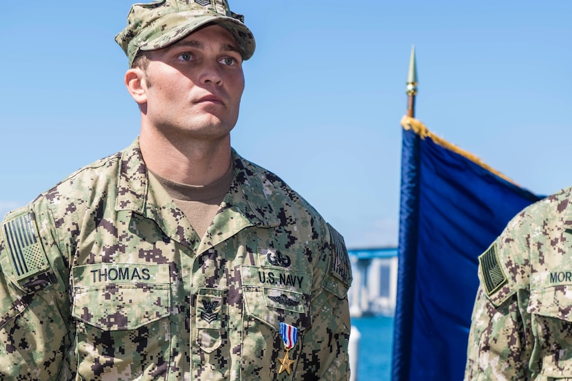 A sailor stands at attention wearing a Silver Star on his uniform.