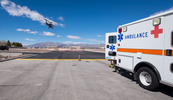 A helicopter lands behind an ambulance.