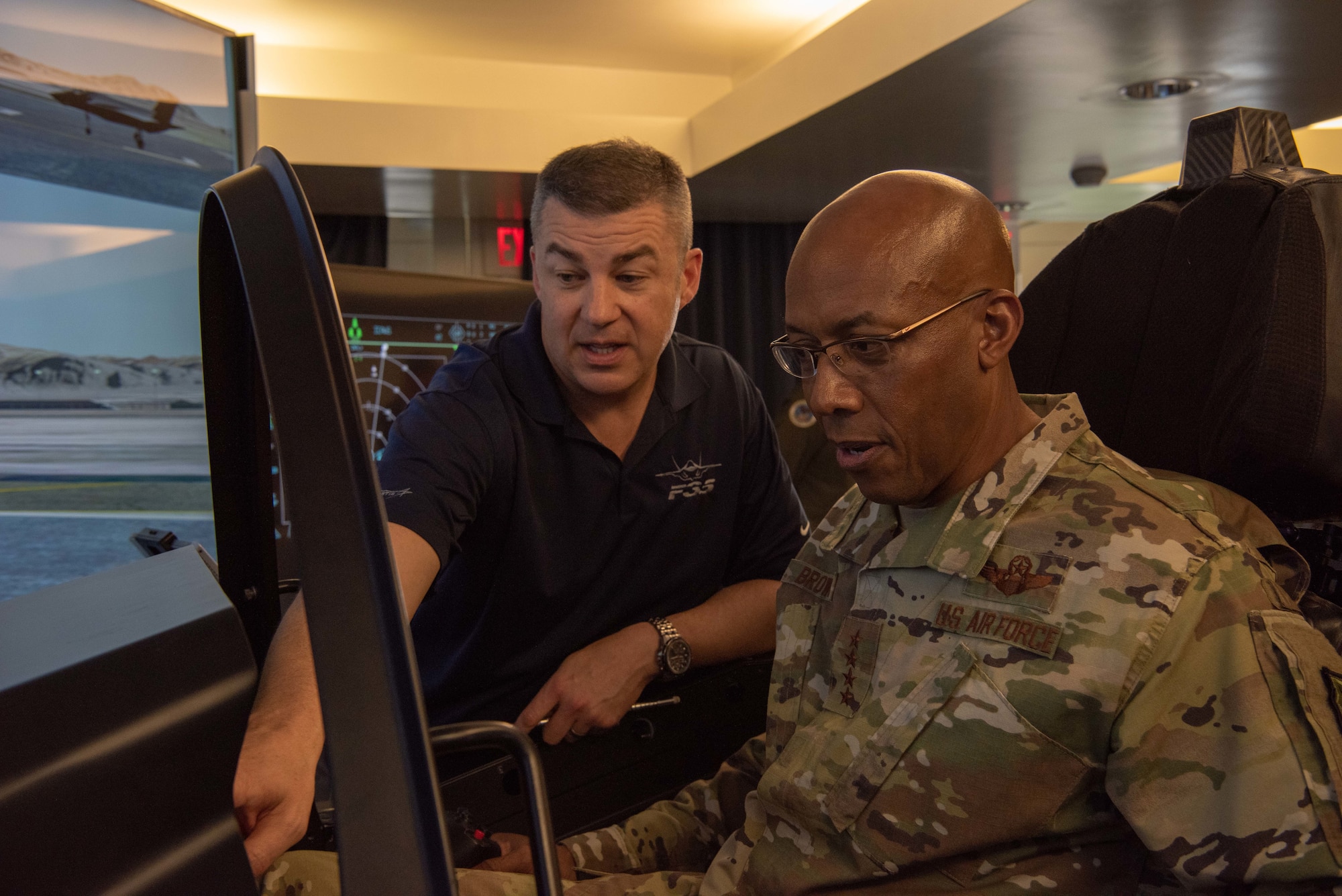 Adrean Clark, Lockheed Martin Operations analyst, demonstrates how to read the displays in the F-35 simulator to U.S. Air Force Gen. CQ Brown, Jr., Pacific Air Forces commander, during the Pacific F-35 Users Group Conference at Joint Base Pearl Harbor-Hickam, Hawaii, March 12, 2019.