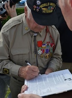 Alfred Bucci, a D-Day Veteran, signs a book for a fan during the Carre de Choux Ceremony in Carentan, France