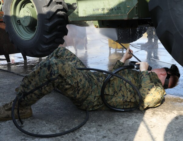 U.S. Marine Corps Lance Cpl. Audie Rooks pressure washes the underside of a backhoe March 13, 2019 on Camp Kinser, Okinawa, Japan. The backhoe is one of many pieces of equipment that are cleaned, inspected and then shipped for use in Australia by the Marine Rotational Force – Darwin Marine Air-Ground Task Force. Rooks, a heavy equipment operator with Heavy Equipment Operations Platoon, Engineer Support Company, 9th Engineer Support Battalion, 3rd Marine Logistics Group, is a native of Hawkinsville, Georgia. (U.S. Marine Corps photo by Cpl. Isabella Ortega)