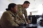 Tech. Sgt. Kathryn Glenn, 380th Expeditionary Logistics Readiness Squadron NCOIC, logistics plans, and Capt. Mark Dellaquila, 380th ELRS Installation Deployment Officer, answers a call about redeployments at Al Dhafra Air Base, United Arab Emirates, Mar. 14, 2019.