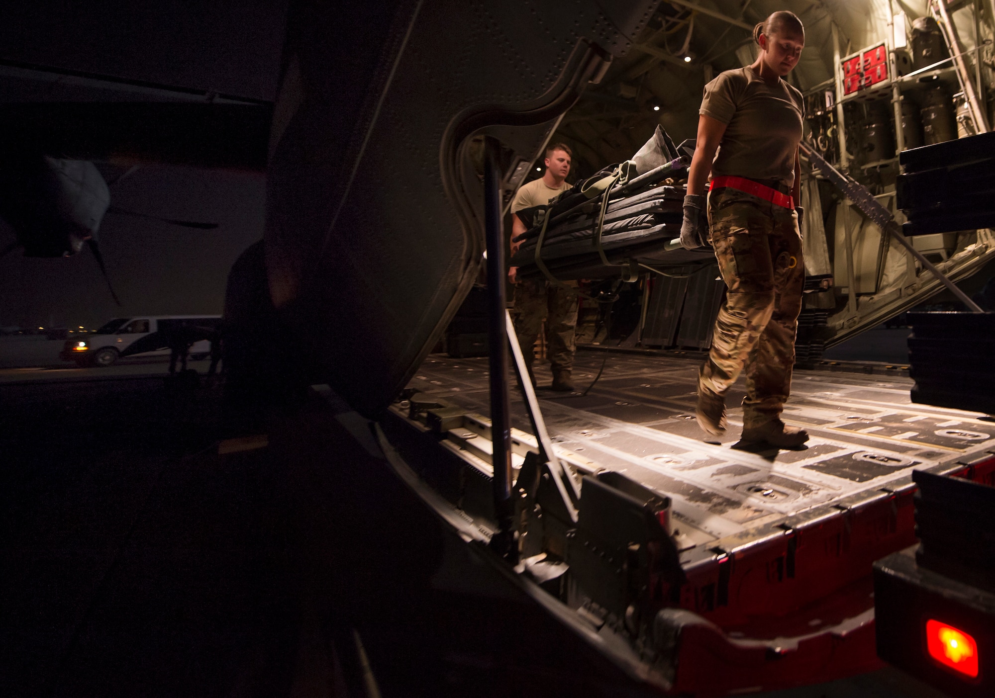 From left, Senior Airman Robert McCabe and Staff Sgt. Lyndsey Glotfelty, 379th Expeditionary Aeromedical Evacuation Squadron (EAES) aeromedical evacuation technicians, move medical equipment onto a truck at Al Udeid Air Base, Qatar, after a recent aeromedical evacuation.