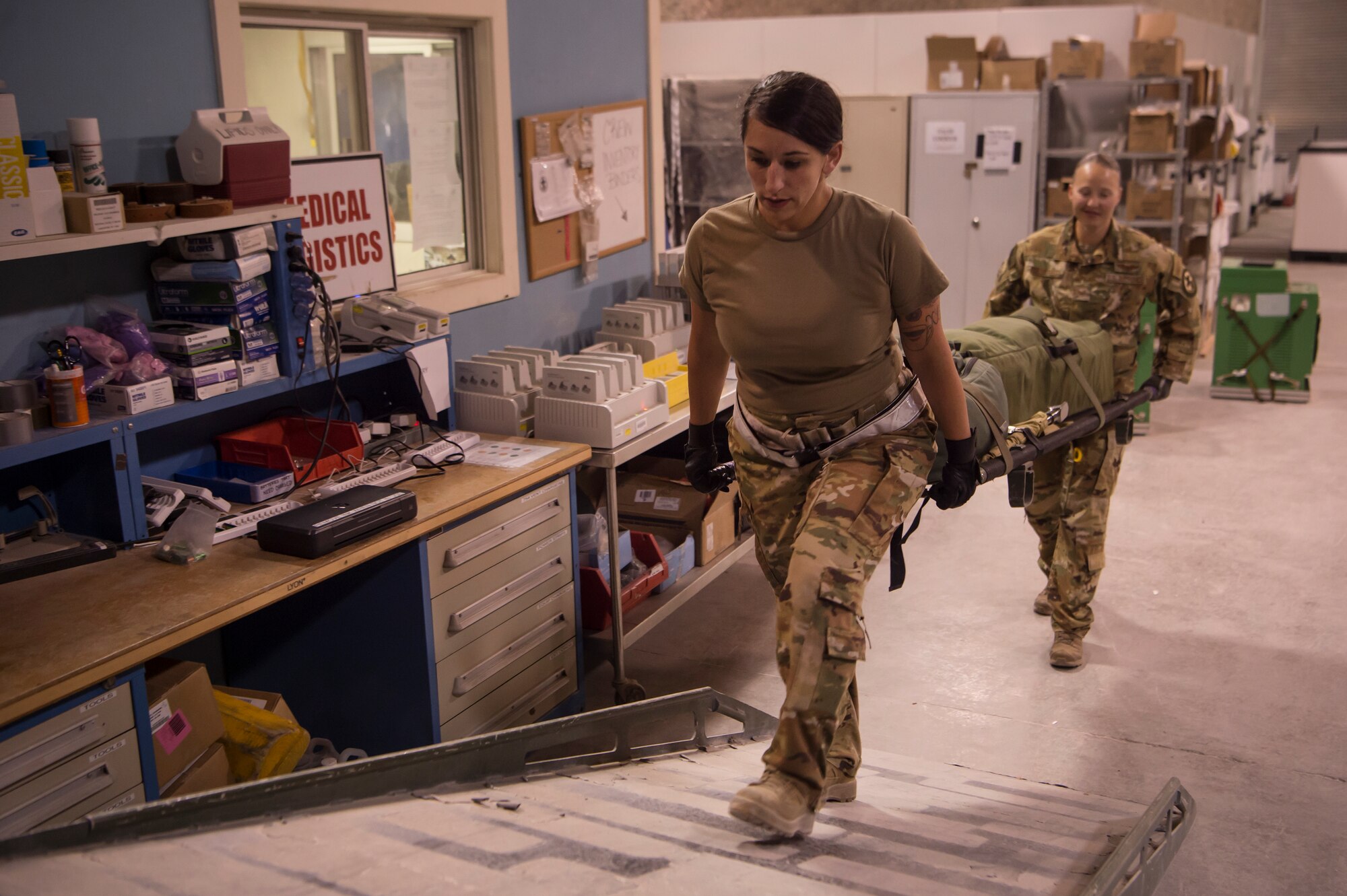 Staff Sgt. Monica Otholt, left, 379th Expeditionary Aeromedical Evacuation Squadron (EAES) duty controller, and Staff Sgt. Lyndsey Glotfelty, 379th EAES aeromedical evacuation technician, move medical equipment onto the back of a truck at Al Udeid Air Base, Qatar, before a recent mission.